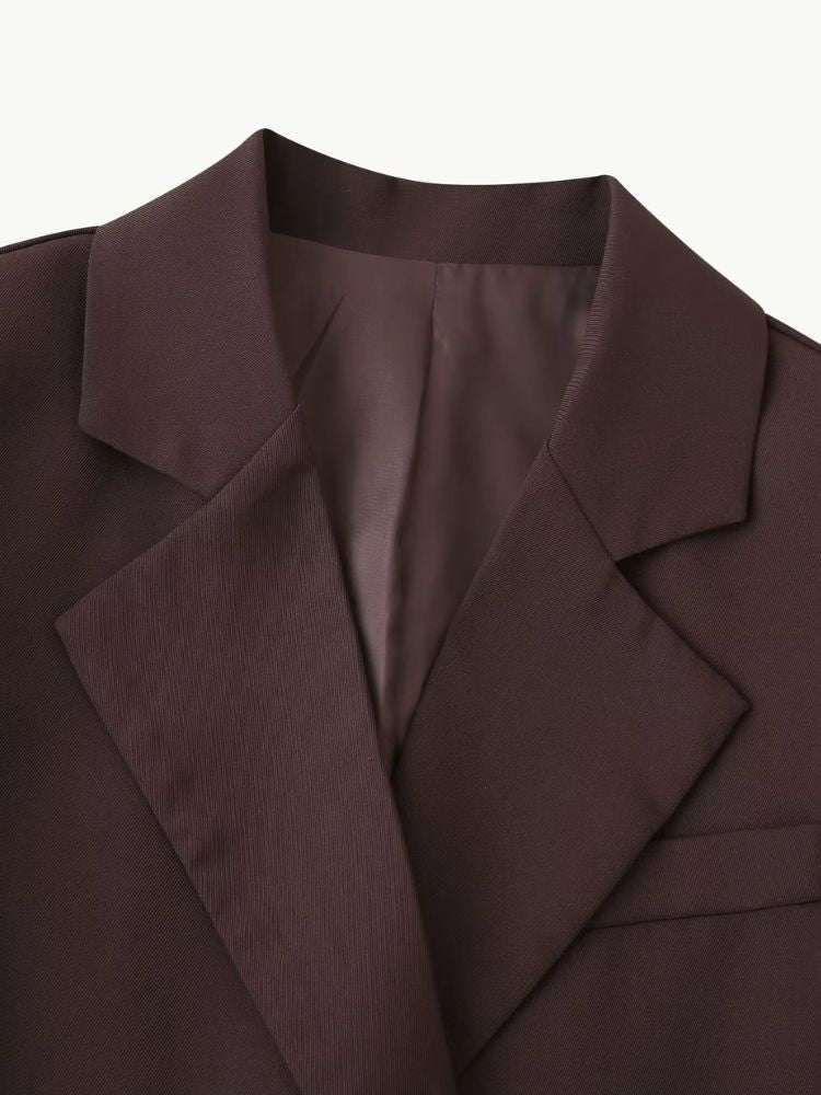 Close no detalhe da gola lapela chanfrada e estruturada do blazer marrom feminino, evidenciando o acabamento premium exclusivo Moda Origem
