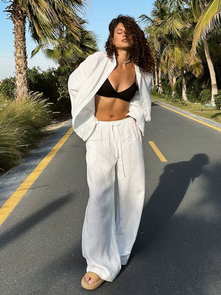 Modelo de frente exibindo o look completo com o conjunto feminino em linho branco de camisa oversized e calça pantalona na Moda Origem