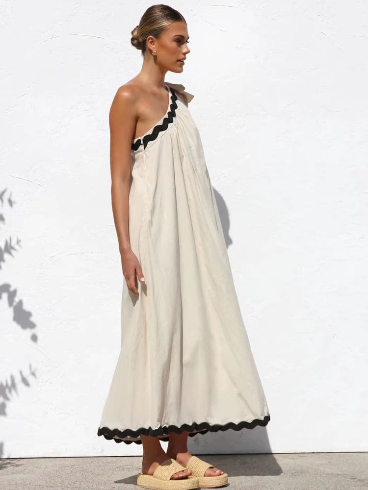 Vista lateral do vestido longo bege um ombro só com babado preto, Moda Origem